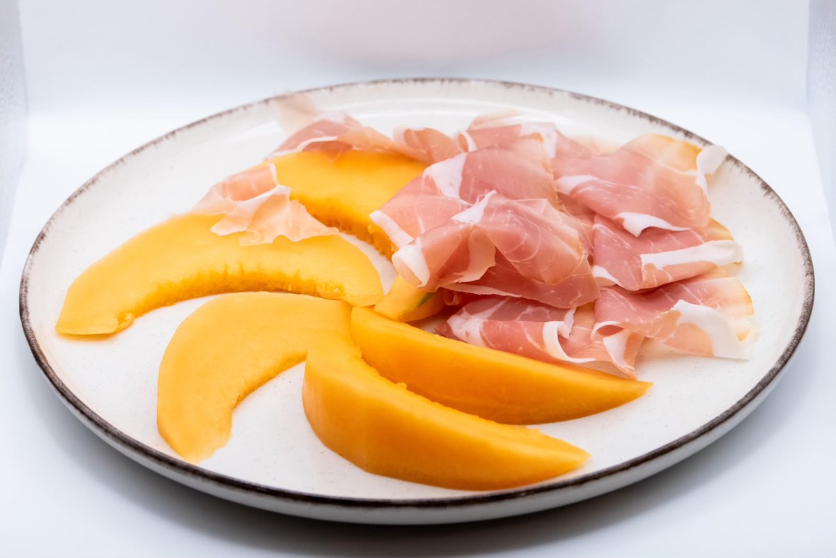 Piatto di prosciutto crudo affettato servito con fette di melone