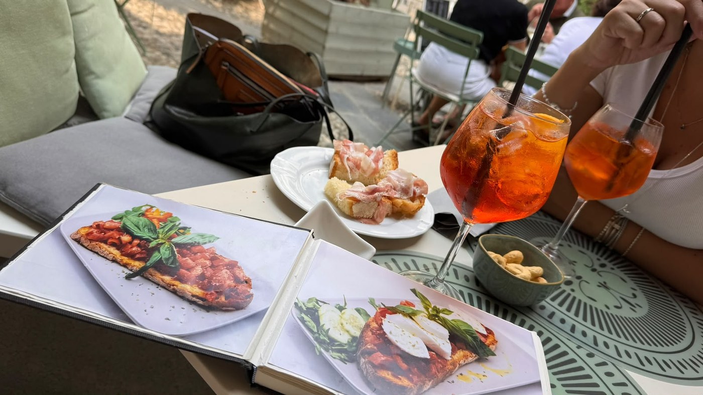 Tavolo nella corte del Bistrot Vivè con tagliere di salumi e aperitivo